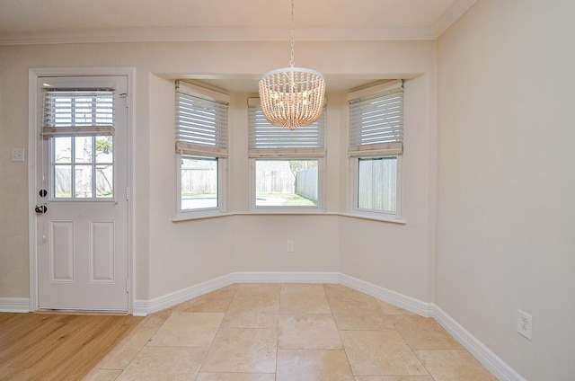 unfurnished dining area with baseboards, a notable chandelier, and crown molding