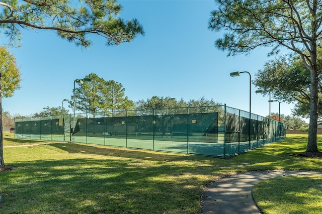 view of tennis court featuring a yard and fence