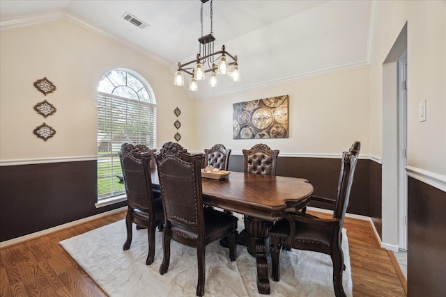 dining room with visible vents, wood finished floors, crown molding, and vaulted ceiling