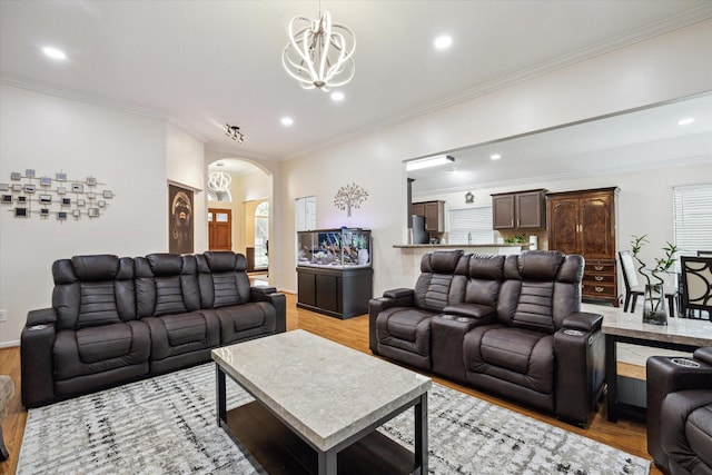 living room with light wood-style floors, arched walkways, a chandelier, and ornamental molding