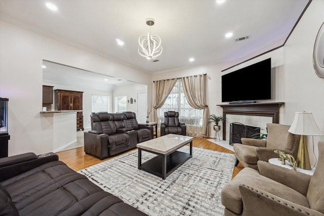 living area featuring visible vents, a chandelier, light wood-type flooring, ornamental molding, and a tile fireplace