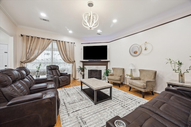 living area with visible vents, wood finished floors, ornamental molding, and a tile fireplace