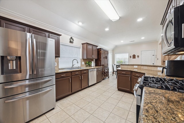 kitchen with light tile patterned floors, a sink, decorative backsplash, stainless steel appliances, and dark brown cabinets