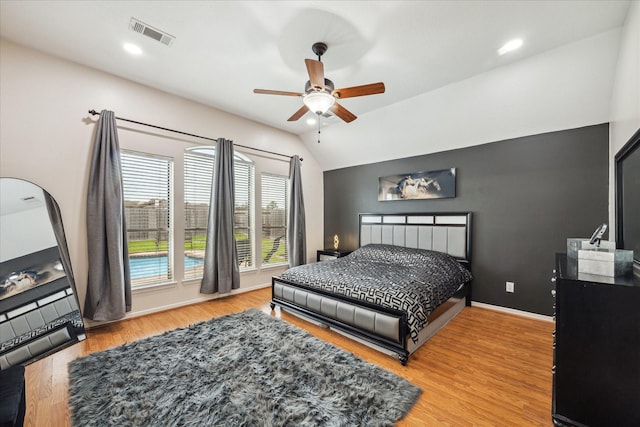 bedroom with visible vents, baseboards, vaulted ceiling, wood finished floors, and a ceiling fan