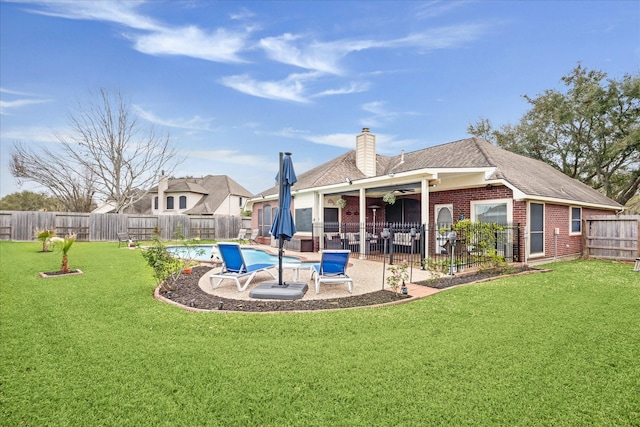 back of property featuring a lawn, a patio, a fenced backyard, a fenced in pool, and brick siding