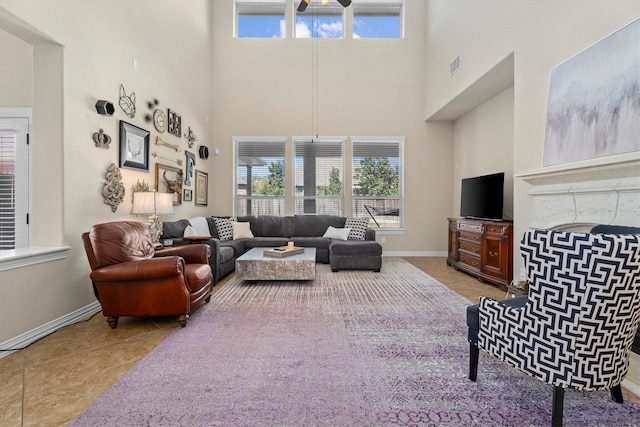 living area with a towering ceiling, visible vents, baseboards, and tile patterned floors