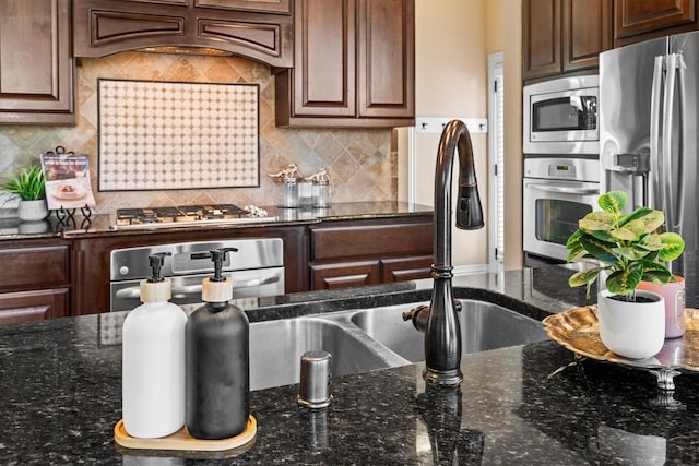 kitchen featuring dark stone counters, appliances with stainless steel finishes, custom exhaust hood, and decorative backsplash