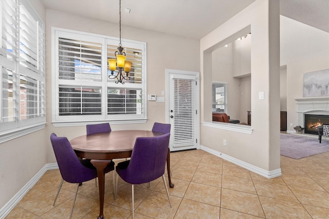 tiled dining space featuring a wealth of natural light, a glass covered fireplace, and baseboards