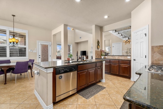 kitchen featuring light tile patterned flooring, dishwasher, backsplash, and dark stone countertops