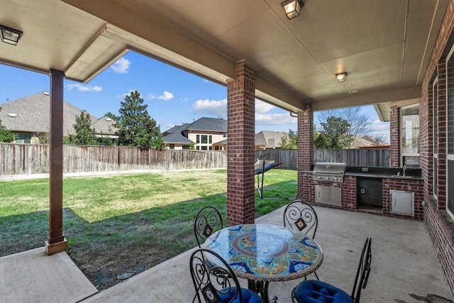 view of patio / terrace featuring exterior kitchen, a fenced backyard, a grill, and outdoor dining area