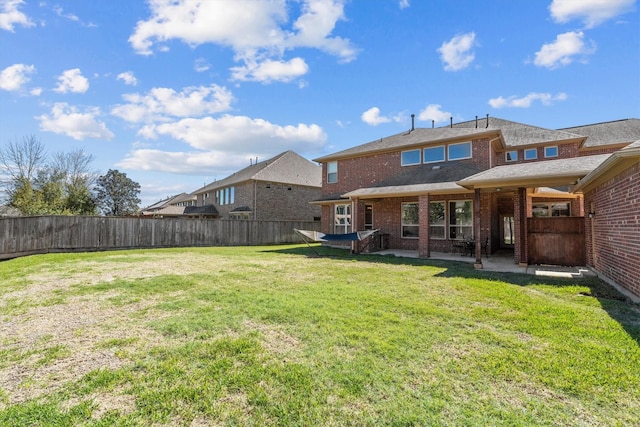 rear view of property with a patio, a yard, a fenced backyard, and brick siding