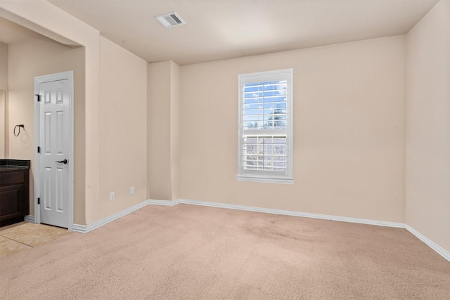 empty room with baseboards, visible vents, and light colored carpet