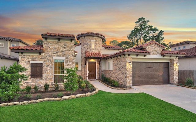 mediterranean / spanish-style house with a garage, concrete driveway, a yard, and stone siding