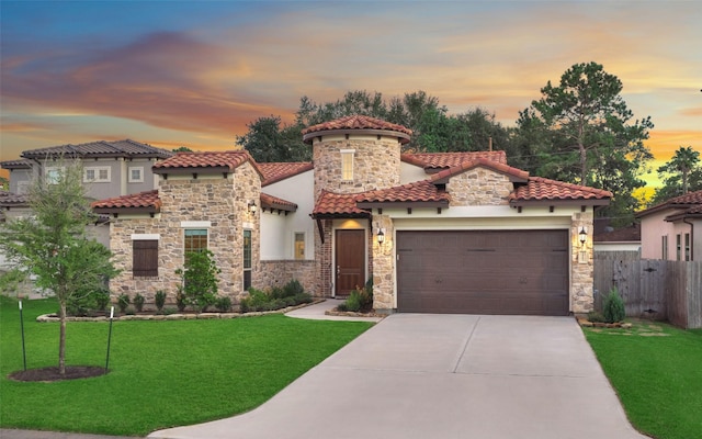 mediterranean / spanish home featuring a yard, concrete driveway, an attached garage, fence, and a tiled roof