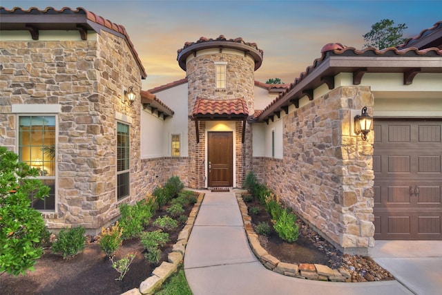 view of exterior entry featuring a tiled roof and an attached garage