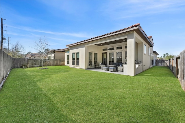 back of property featuring a lawn, a patio, ceiling fan, a fenced backyard, and stucco siding