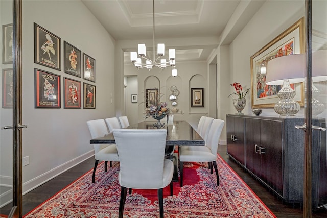 dining area featuring baseboards, a raised ceiling, dark wood-style flooring, an inviting chandelier, and crown molding