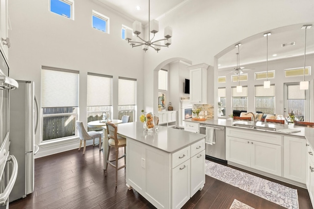 kitchen featuring appliances with stainless steel finishes, dark wood-style flooring, light countertops, white cabinetry, and a sink