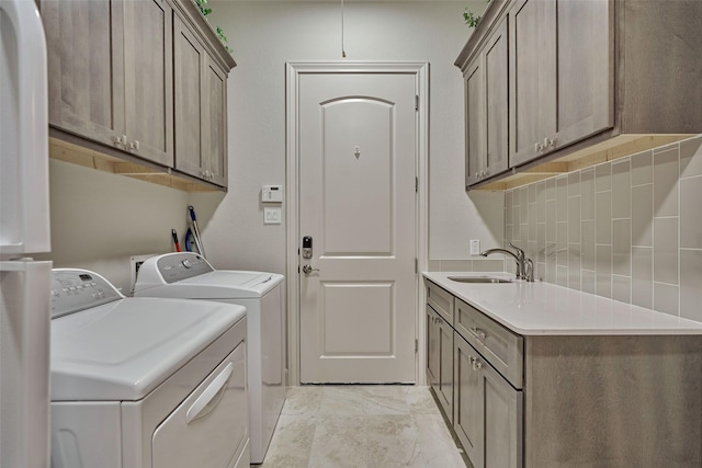 clothes washing area with cabinet space, washer and dryer, and a sink