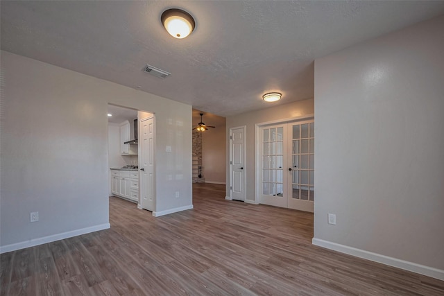 empty room featuring french doors, visible vents, dark wood finished floors, and baseboards