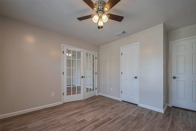 spare room featuring baseboards, visible vents, ceiling fan, wood finished floors, and french doors