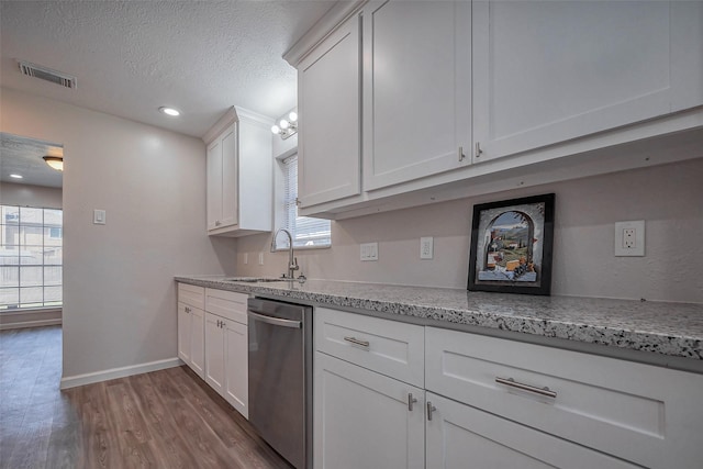 kitchen featuring visible vents, white cabinets, dishwasher, a textured ceiling, and a sink