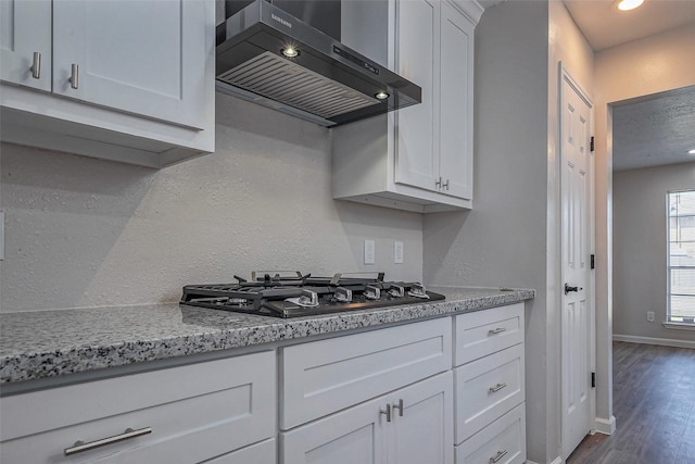 kitchen featuring baseboards, white cabinets, dark wood finished floors, ventilation hood, and gas stovetop