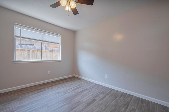 empty room with ceiling fan, baseboards, and wood finished floors