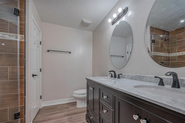 bathroom with visible vents, a tile shower, a sink, and wood finished floors