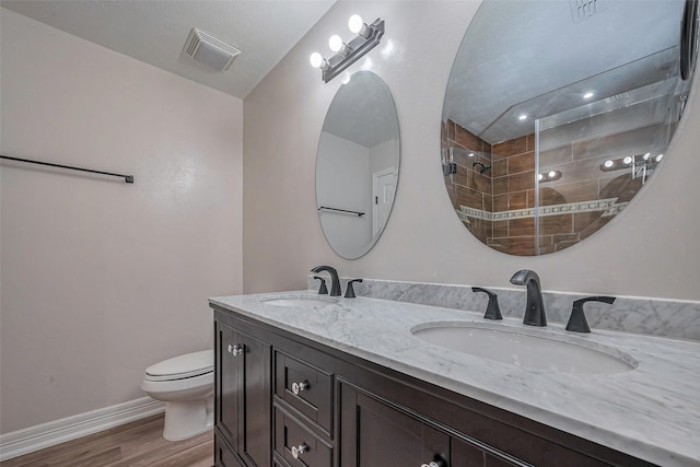 full bathroom featuring toilet, visible vents, a sink, and wood finished floors