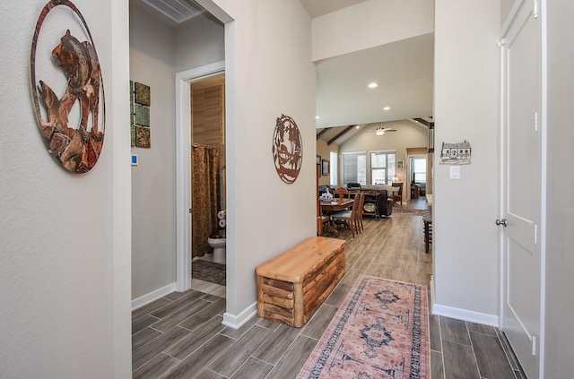 corridor with visible vents, baseboards, lofted ceiling, and wood finish floors