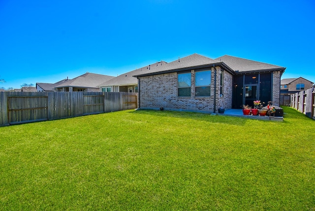 back of property with brick siding, a fenced backyard, and a lawn