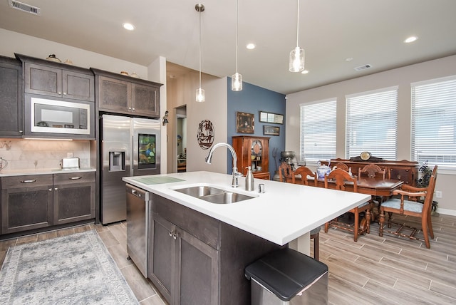 kitchen with tasteful backsplash, visible vents, dark brown cabinets, appliances with stainless steel finishes, and a sink