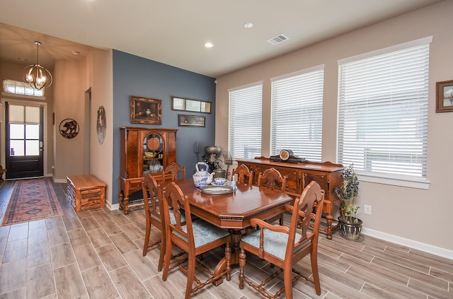 dining area featuring a notable chandelier, a healthy amount of sunlight, visible vents, and wood finish floors