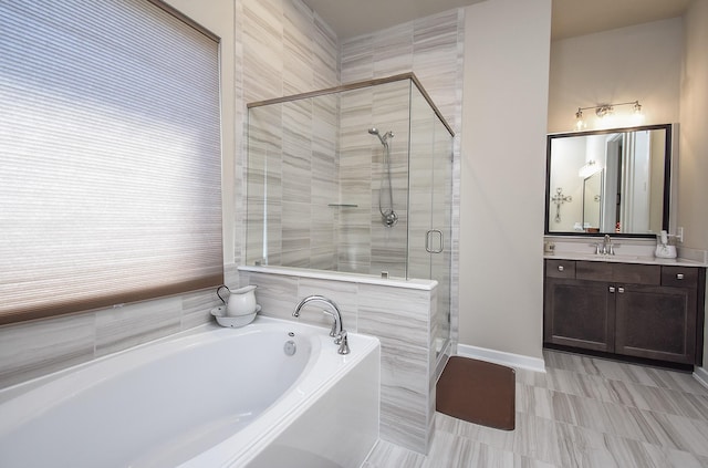 bathroom with a stall shower, baseboards, a bath, and vanity