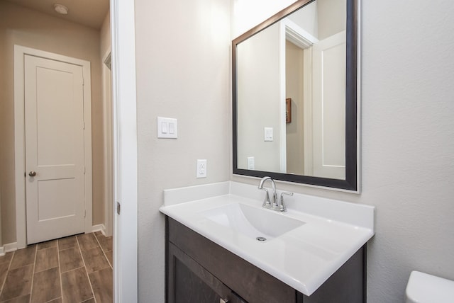 bathroom with toilet, vanity, and wood tiled floor