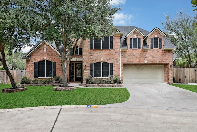 traditional home featuring a front yard, concrete driveway, brick siding, and fence