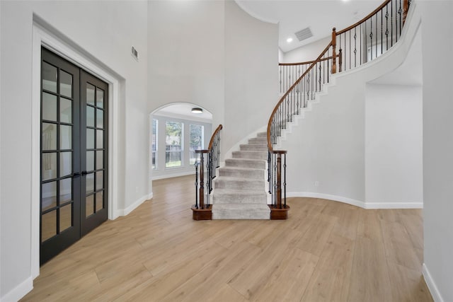 foyer entrance with baseboards, visible vents, wood finished floors, and french doors