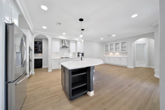 kitchen featuring wall chimney exhaust hood, white cabinets, a sink, and stainless steel fridge with ice dispenser