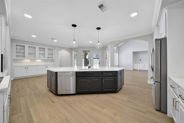 kitchen with appliances with stainless steel finishes, arched walkways, white cabinets, and visible vents