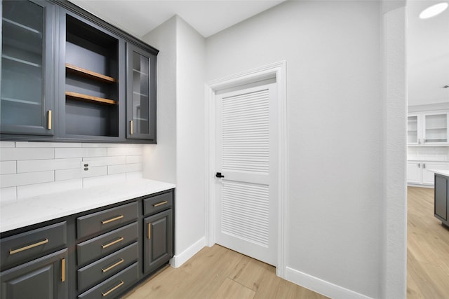 bar with baseboards, light wood finished floors, and decorative backsplash