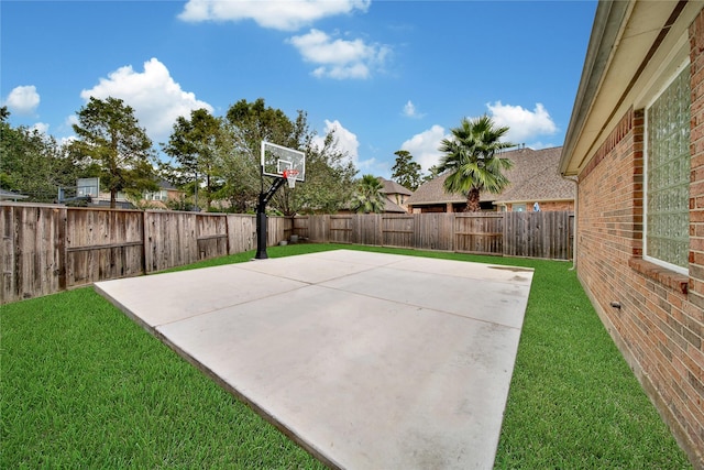 view of sport court featuring basketball court, a fenced backyard, and a yard