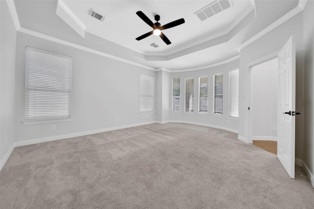 carpeted empty room featuring a raised ceiling, visible vents, crown molding, and baseboards