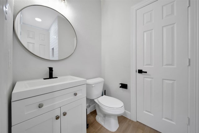 bathroom featuring baseboards, vanity, toilet, and wood finished floors