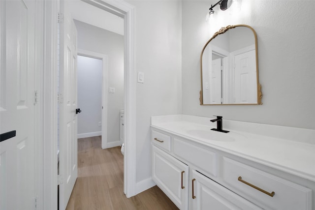 bathroom featuring baseboards, wood finished floors, and vanity