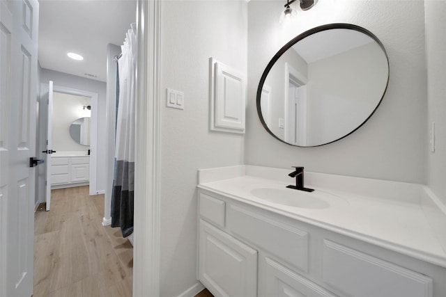 bathroom with recessed lighting, baseboards, wood finished floors, and vanity