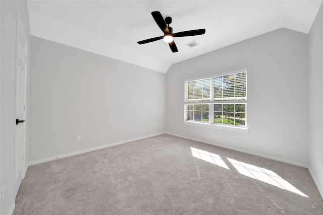 carpeted spare room with lofted ceiling, ceiling fan, visible vents, and baseboards