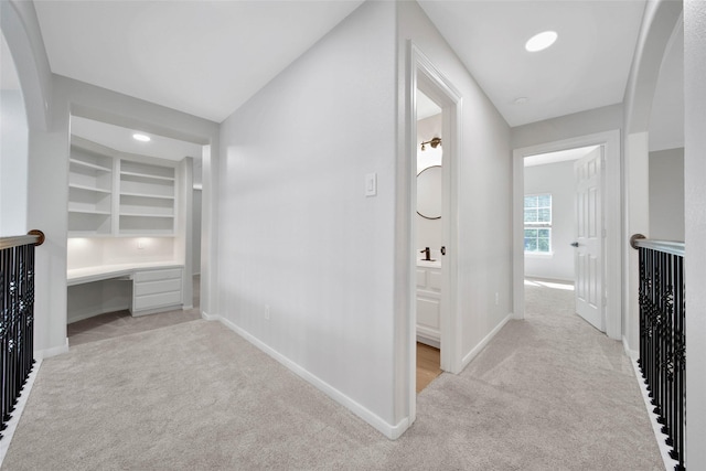 hallway featuring baseboards and light colored carpet