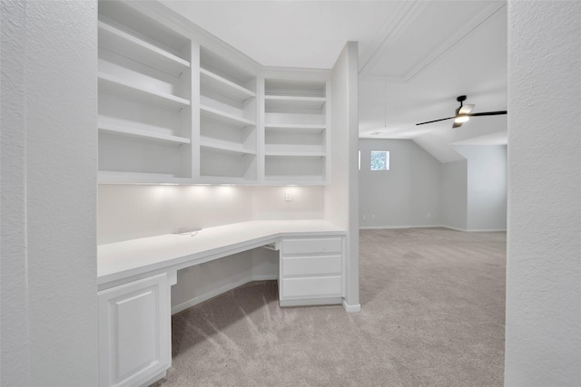 unfurnished office featuring attic access, lofted ceiling, light colored carpet, and built in desk