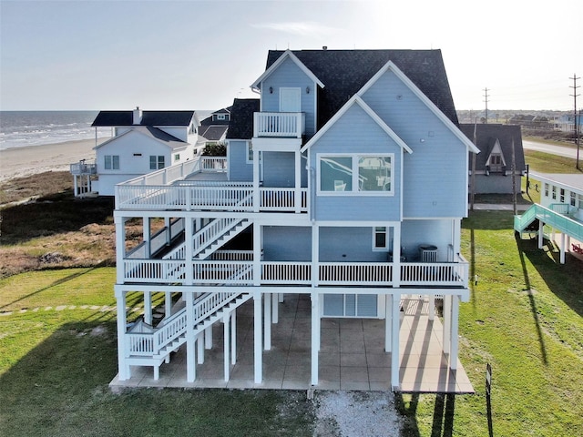 rear view of property with a lawn, a balcony, stairway, a wooden deck, and a patio area